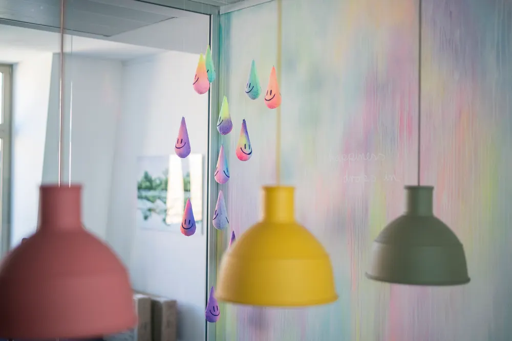 Bunte Pendelleuchten und ein Mobile aus lächelnden Regentropfen im Office